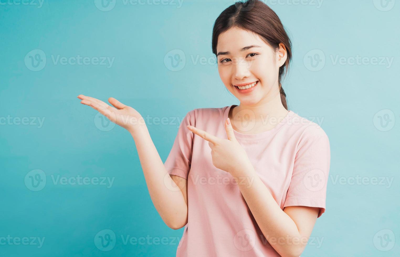 retrato de menina apontando para um lado contra um fundo azul foto