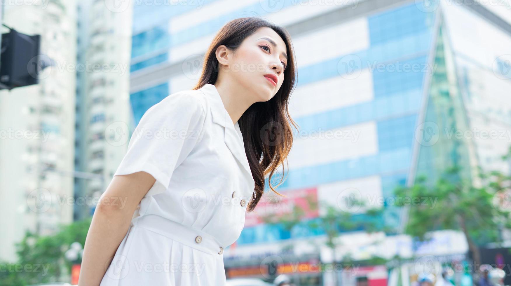 a mulher asiática está esperando o carro pegar foto