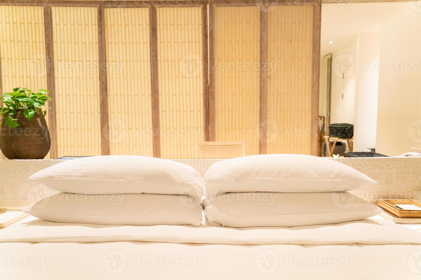 decoração de travesseiros brancos na cama em quarto de hotel resort de luxo foto