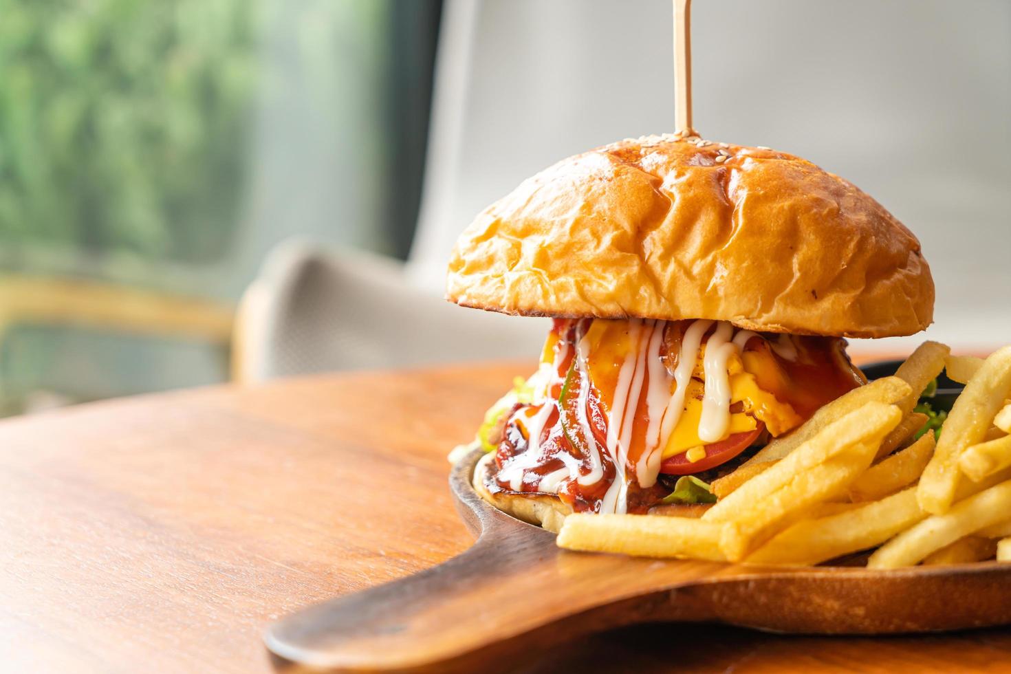 hambúrguer de carne com queijo e molho em prato de madeira foto