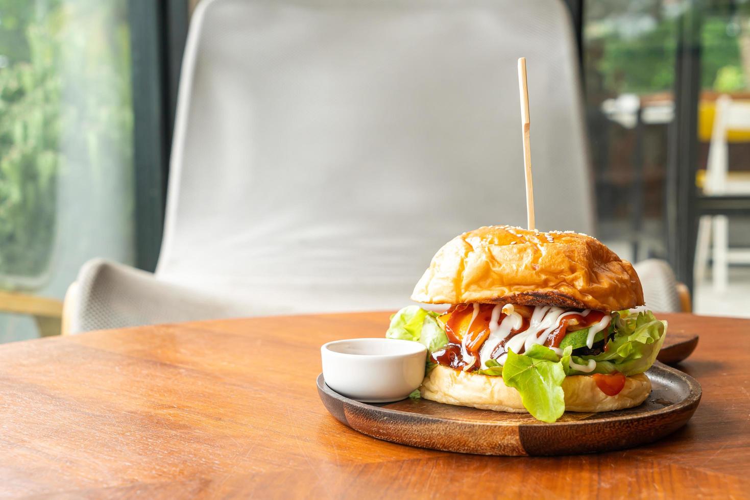 hambúrguer de carne com queijo e molho em prato de madeira foto