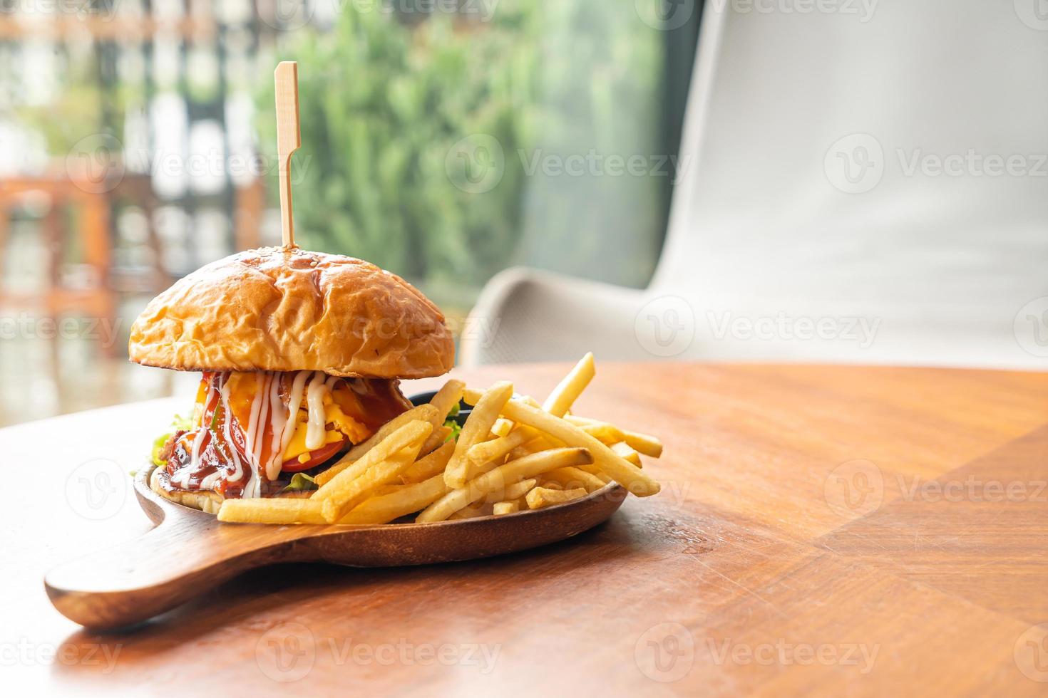 hambúrguer de carne com queijo e molho em prato de madeira foto