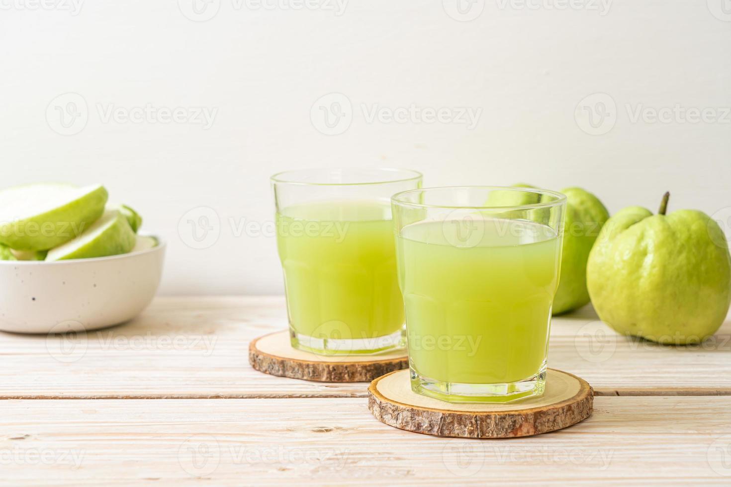 Copo de suco de goiaba fresco com goiaba fresca na mesa de madeira foto