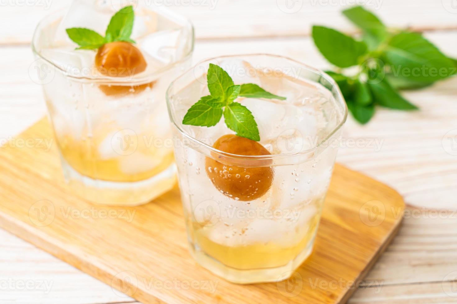 Suco de ameixa gelado com refrigerante e hortelã-pimenta na mesa de madeira - bebida refrescante foto