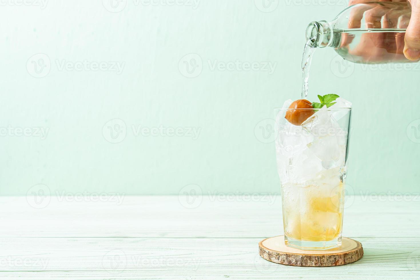 Suco de ameixa gelado com refrigerante e hortelã-pimenta na mesa de madeira - bebida refrescante foto