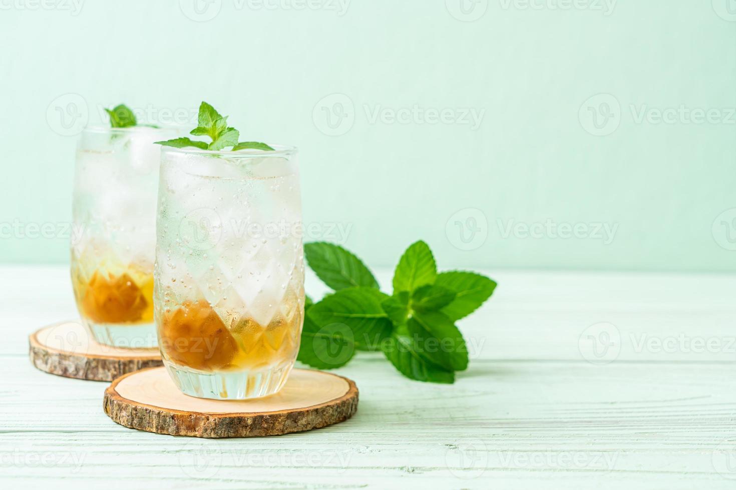 Suco de ameixa gelado com refrigerante e hortelã-pimenta na mesa de madeira - bebida refrescante foto