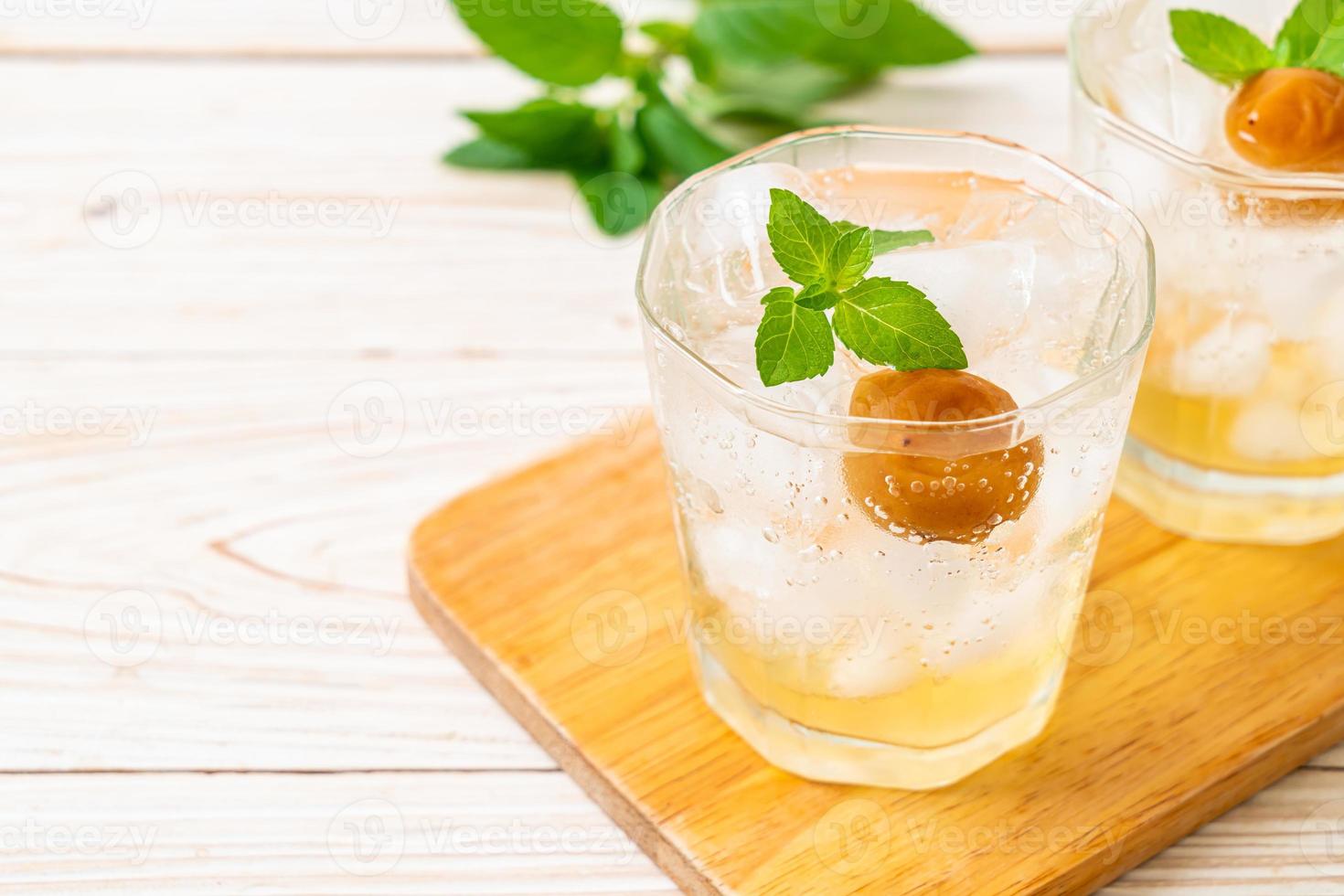 Suco de ameixa gelado com refrigerante e hortelã-pimenta na mesa de madeira - bebida refrescante foto