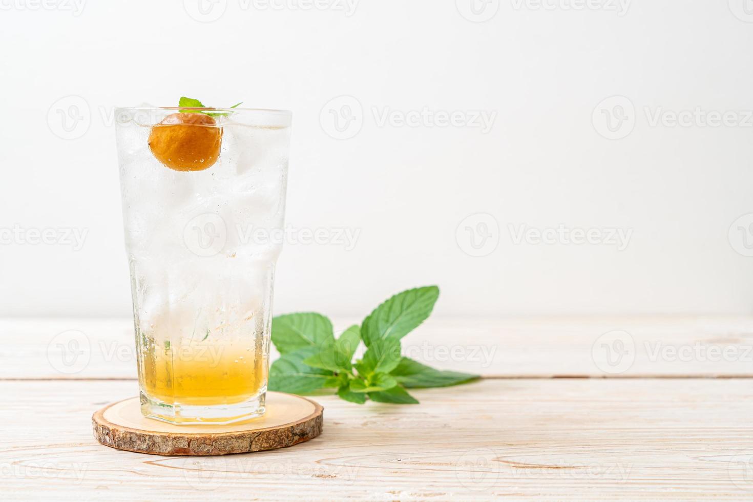 Suco de ameixa gelado com refrigerante e hortelã-pimenta na mesa de madeira - bebida refrescante foto