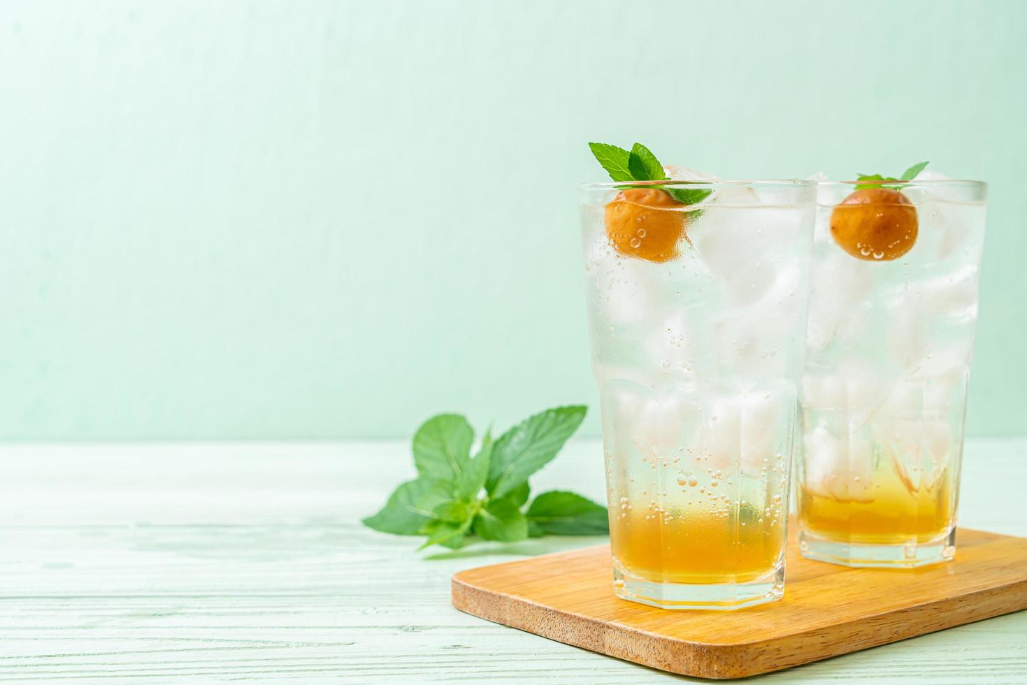 Suco de ameixa gelado com refrigerante e hortelã-pimenta na mesa de madeira - bebida refrescante foto