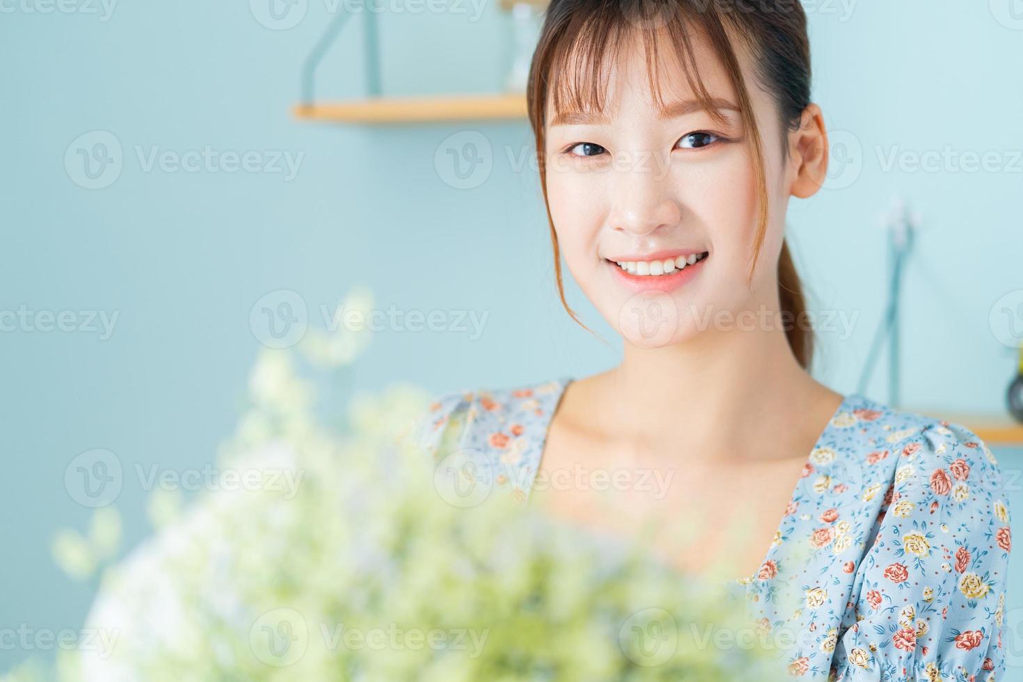 uma jovem mulher asiática segurando flores no quarto dela foto