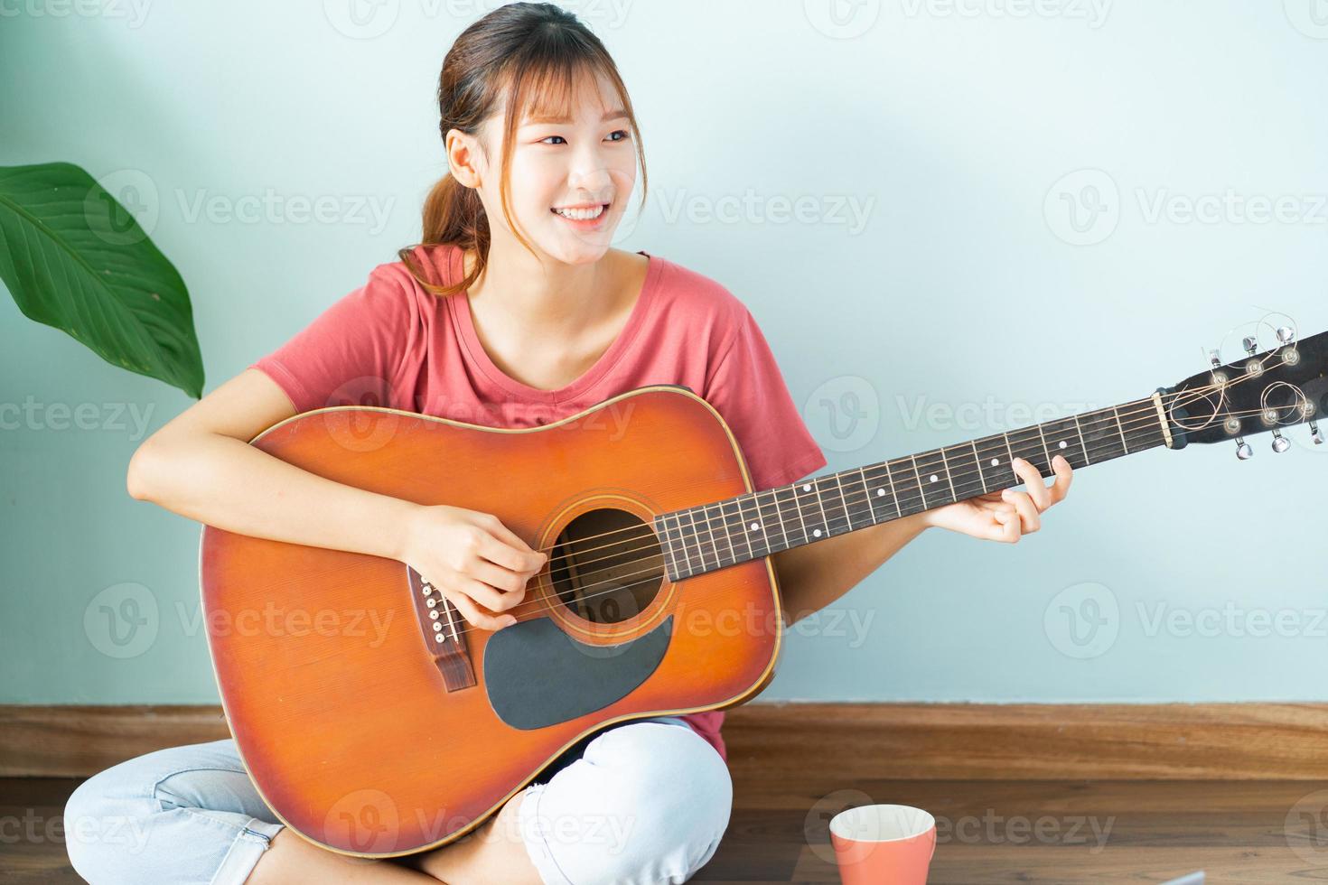 jovem asiática aprendendo violão em casa foto