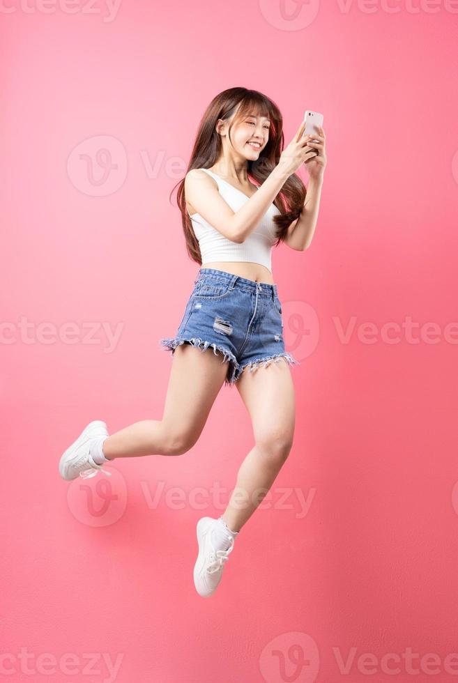 imagem de jovem asiática pulando no fundo rosa foto