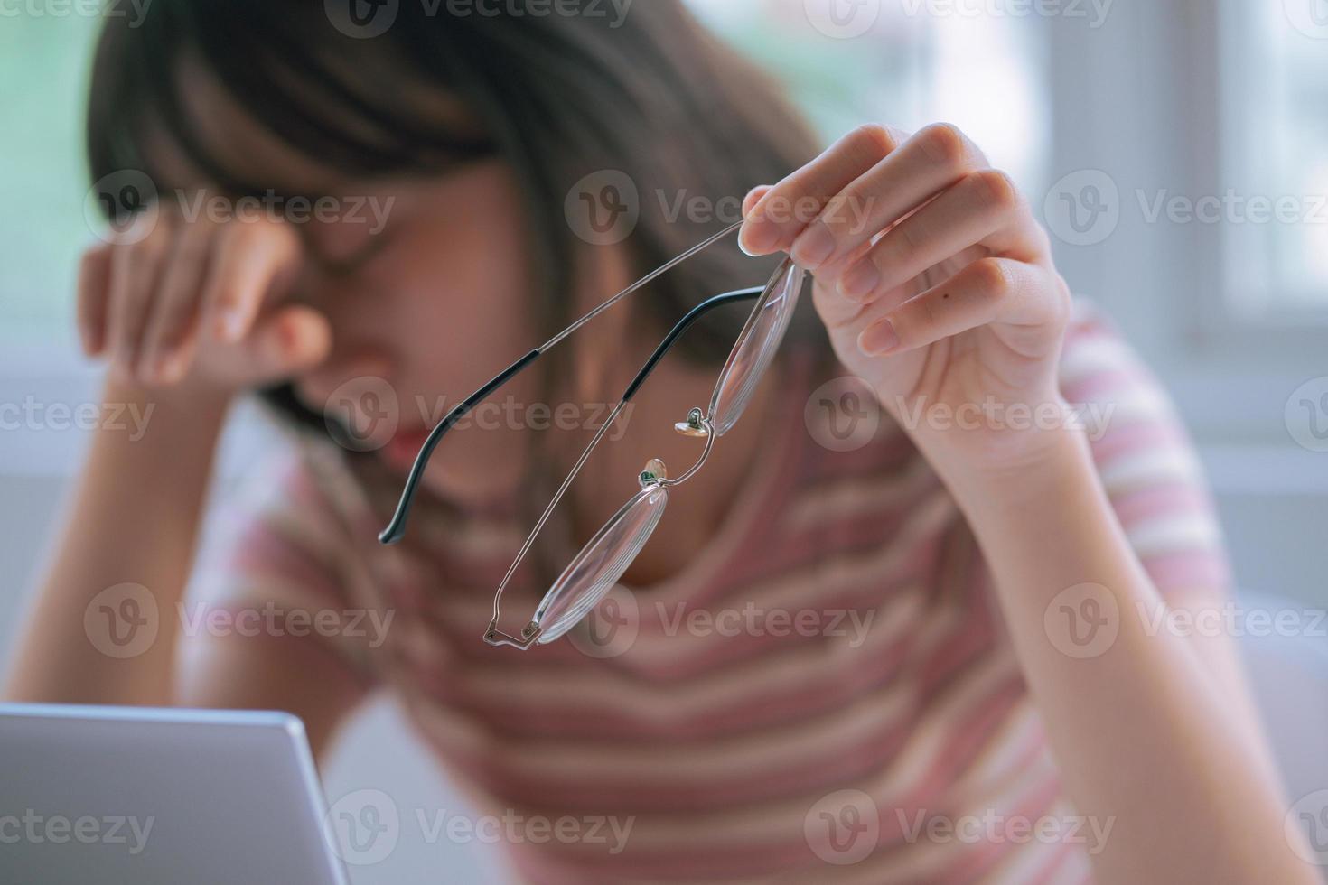 jovem asiática cansada de trabalhar muito tempo no computador foto