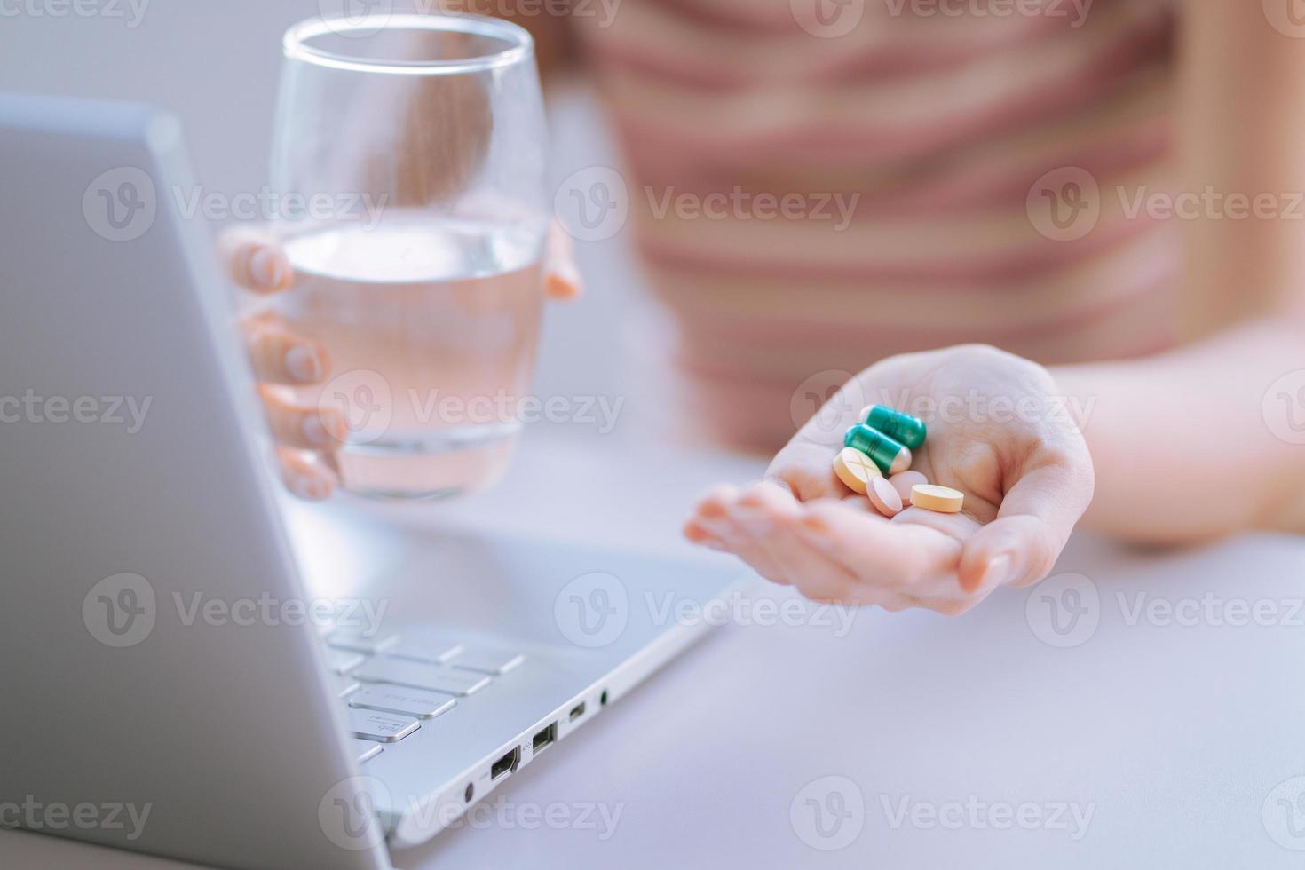 jovem mulher asiática segurando um copo de água e remédio na mão para se preparar para o uso foto