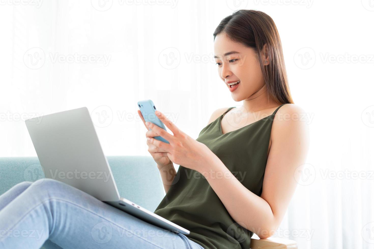 mulher asiática usando laptop e telefone ao mesmo tempo foto