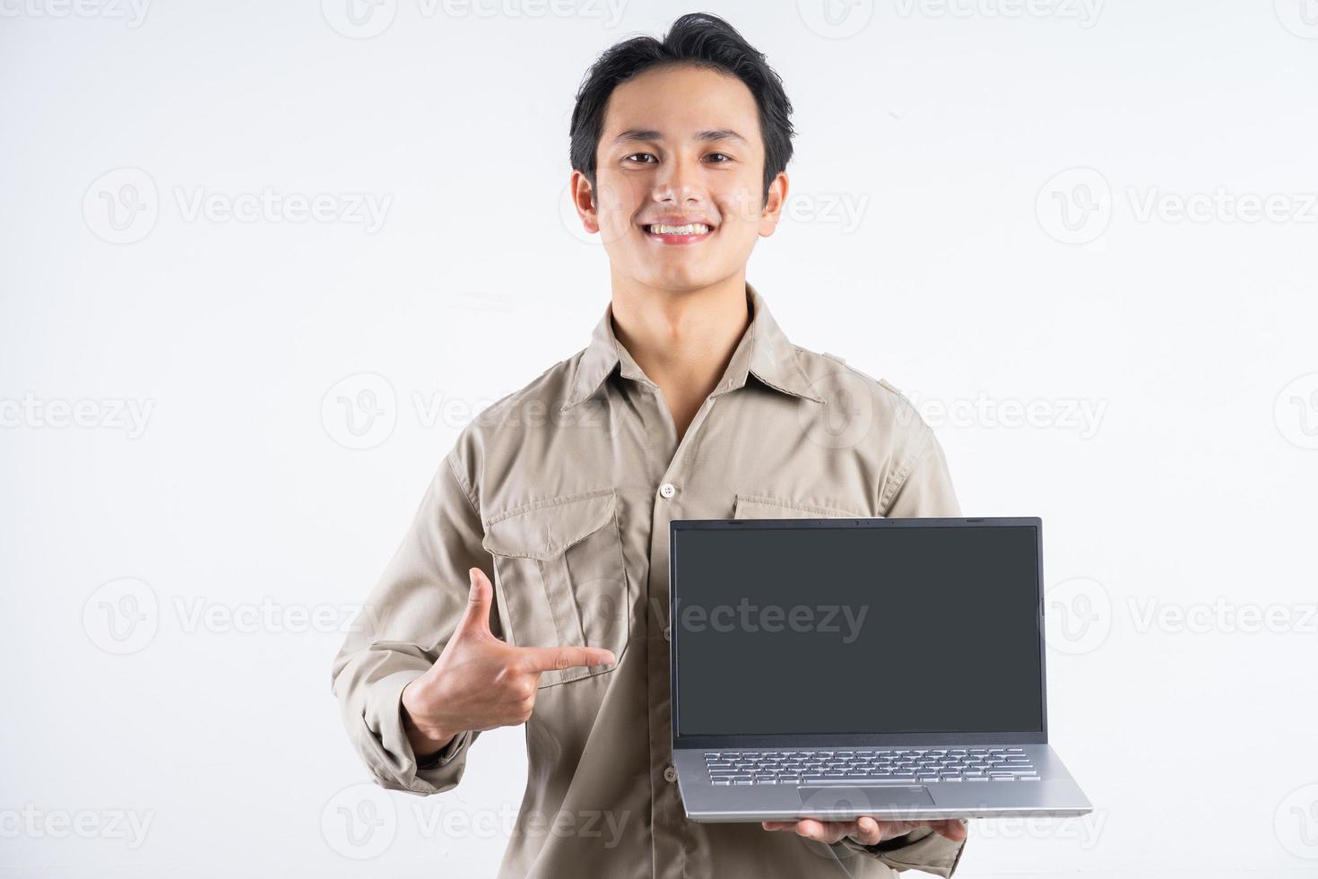 retrato de mecânico masculino em pé com o laptop e apontando para ele no fundo branco foto