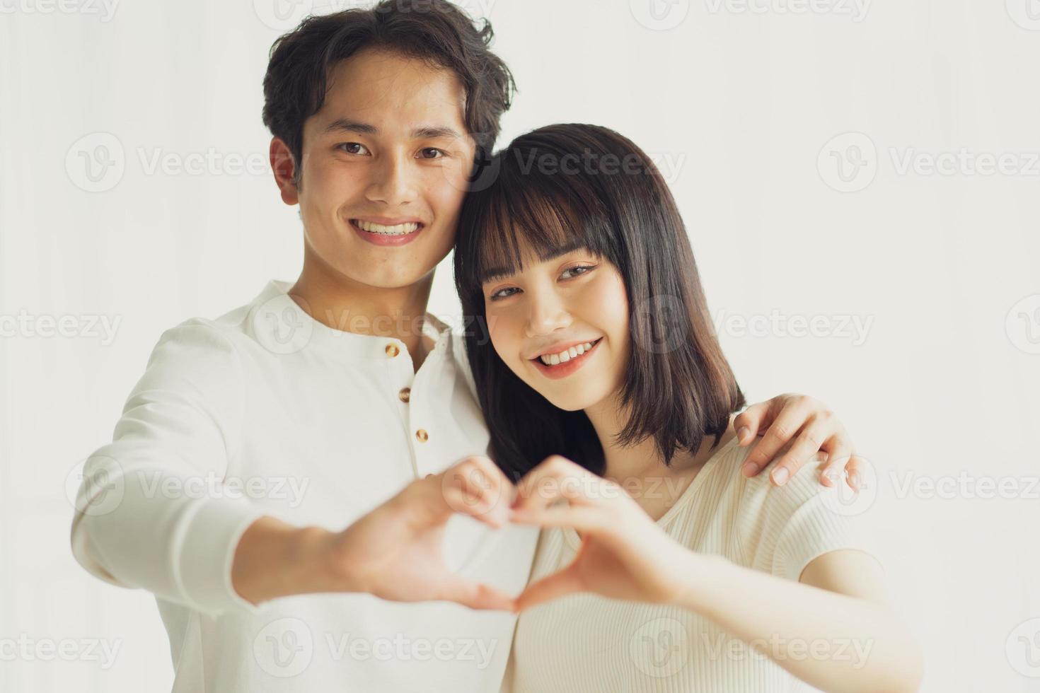 casal asiático fazendo um formato de coração desenhado à mão juntos foto