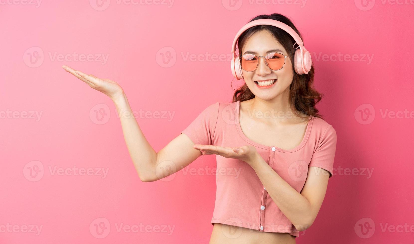 linda garota usando fones de ouvido rosa em um fundo rosa foto