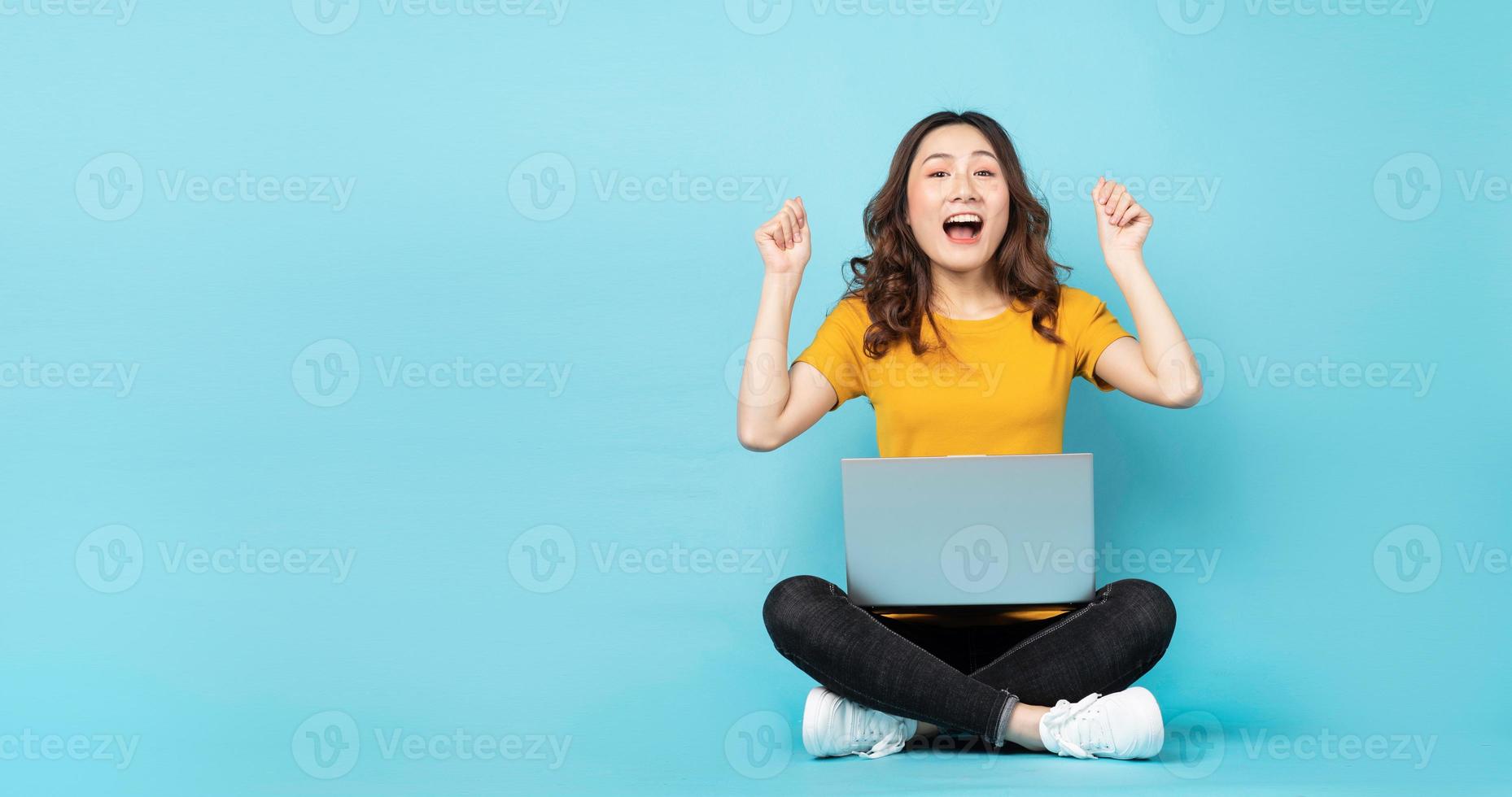 jovem sentada usando laptop com expressões e gestos no fundo foto