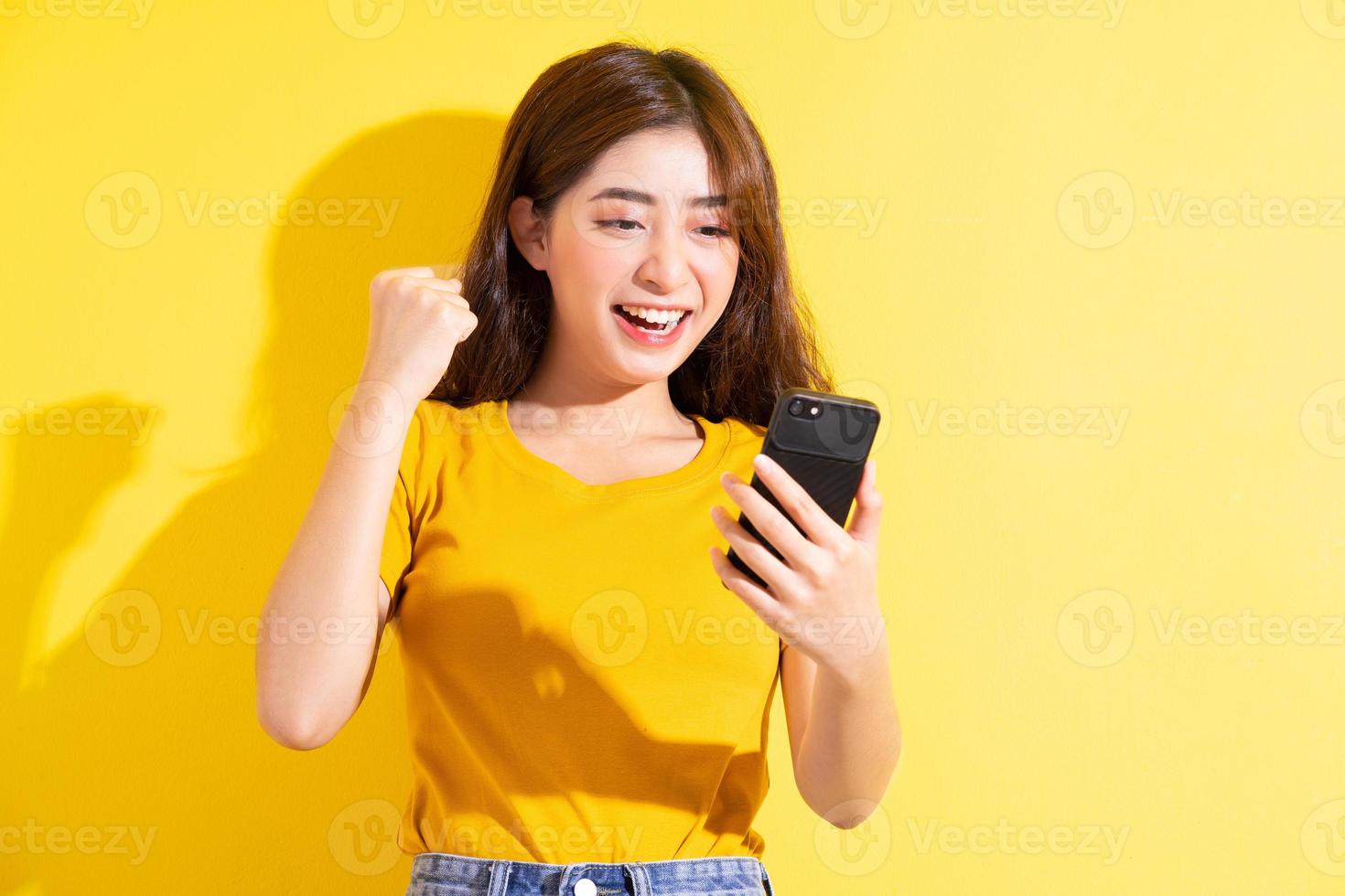 jovem asiática usando smartphone em fundo amarelo foto