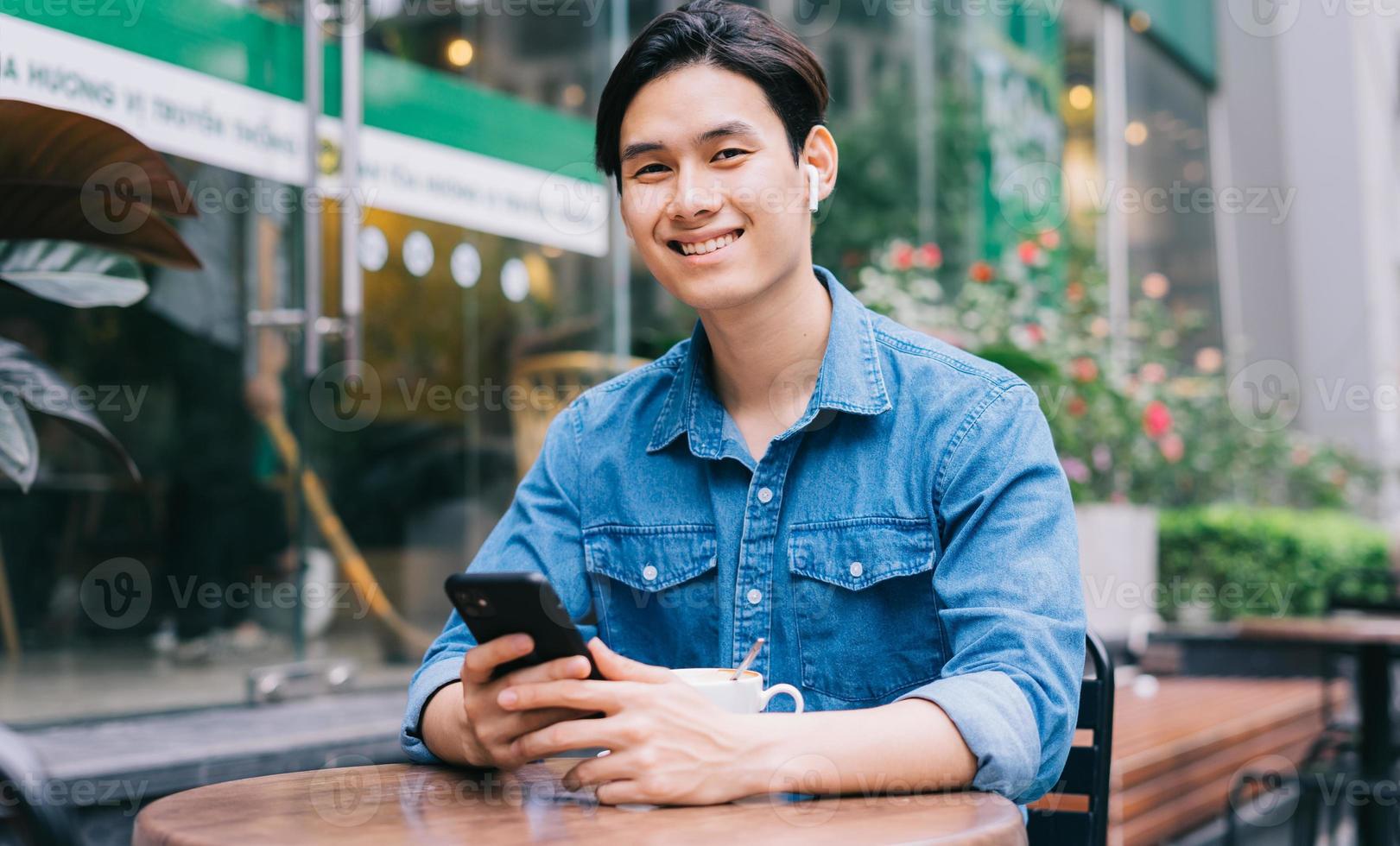 jovem asiático usando smartphone em uma cafeteria foto