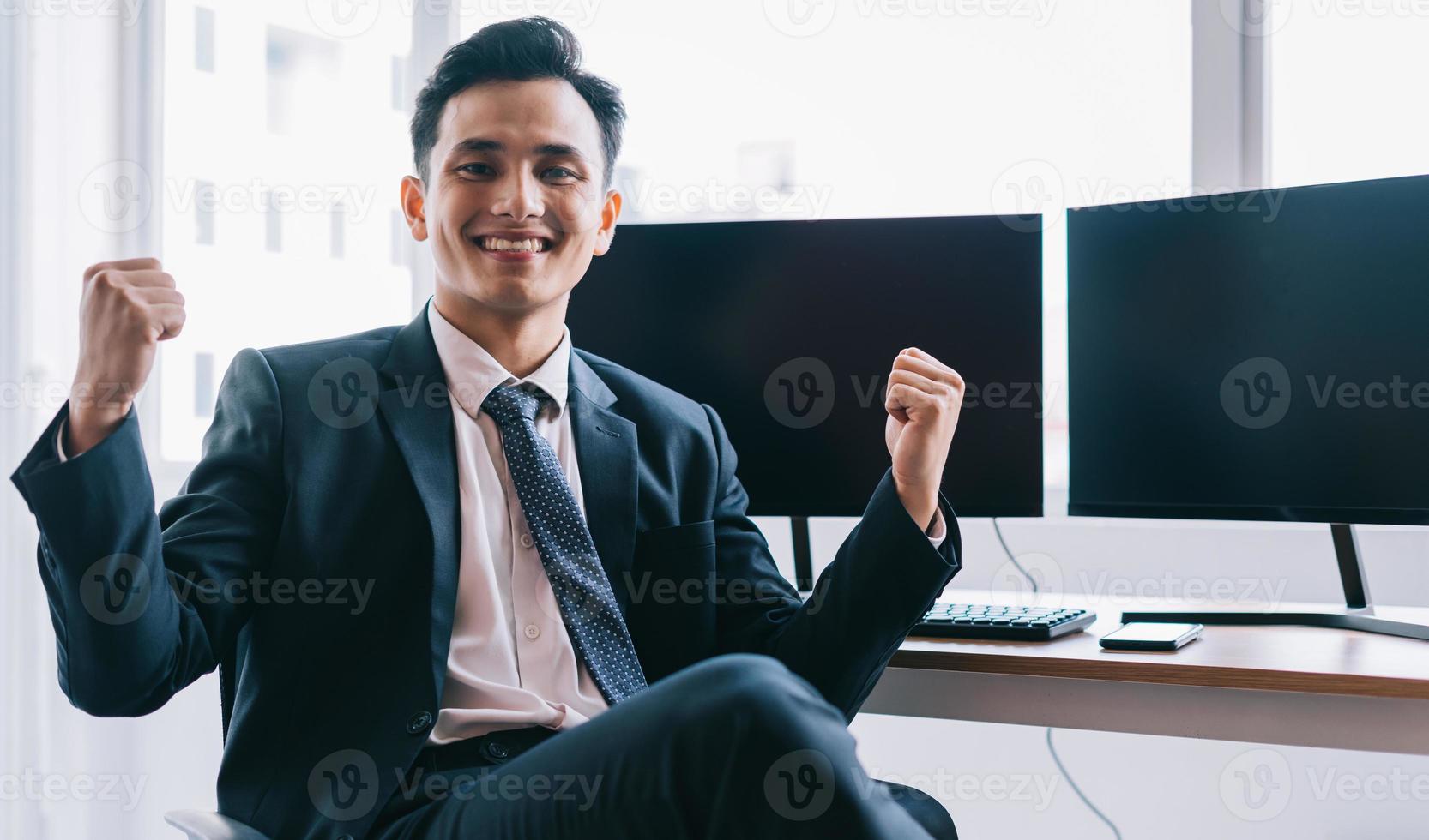 Mulher de negócios asiática está sorrindo com confiança ao lado de duas telas de computador em branco foto