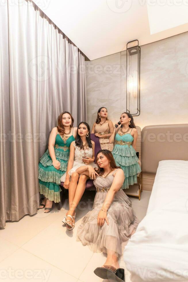 uma grupo do ásia mulheres dentro glamouroso e luxuoso roupas estão sentado em a sofá com seus amigos depois de festa foto