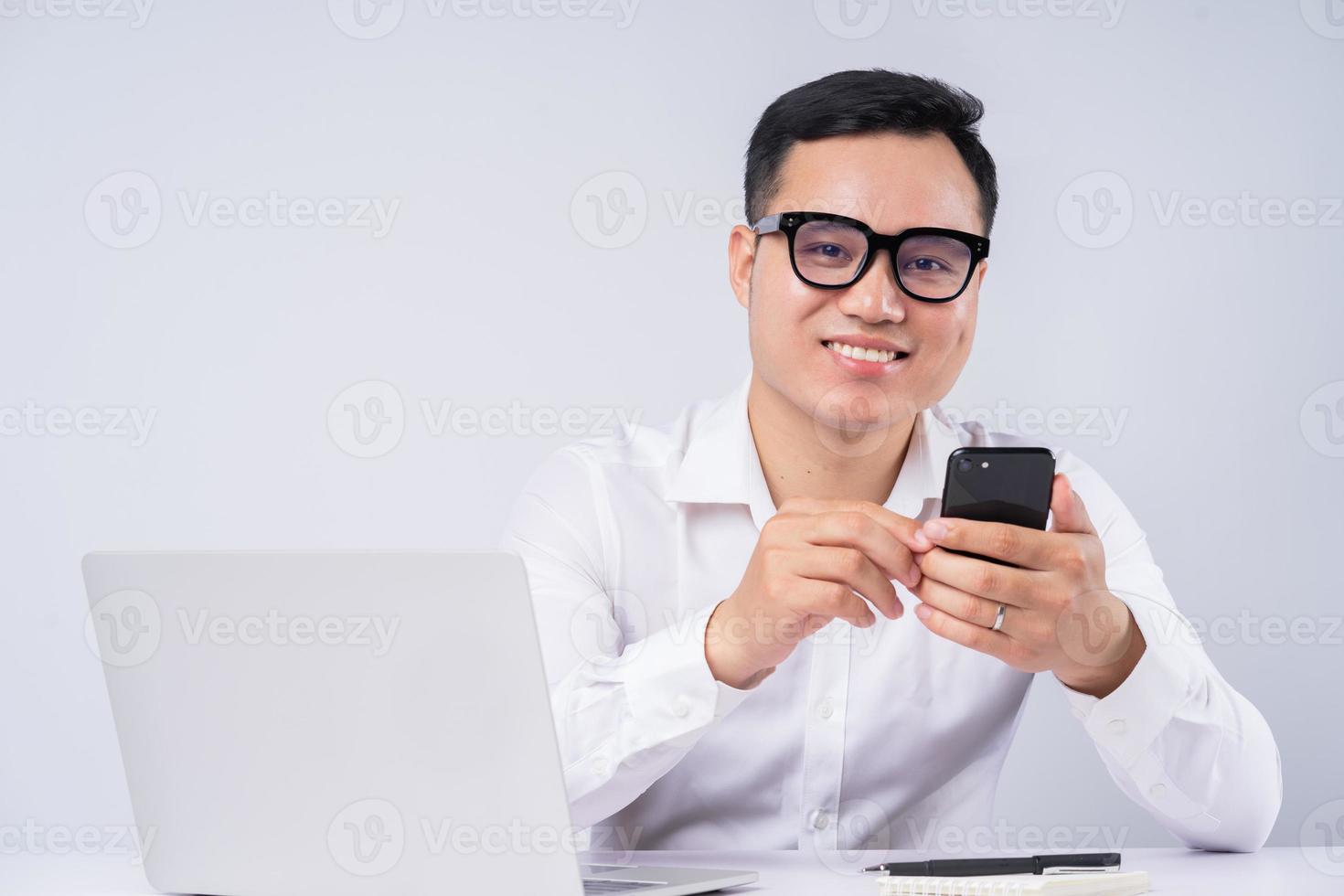 empresário asiático usando smartphone em fundo cinza foto