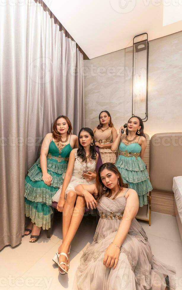 uma grupo do ásia mulheres dentro luxuoso vestidos estão esperando para jantar dentro uma hotel salão de baile foto