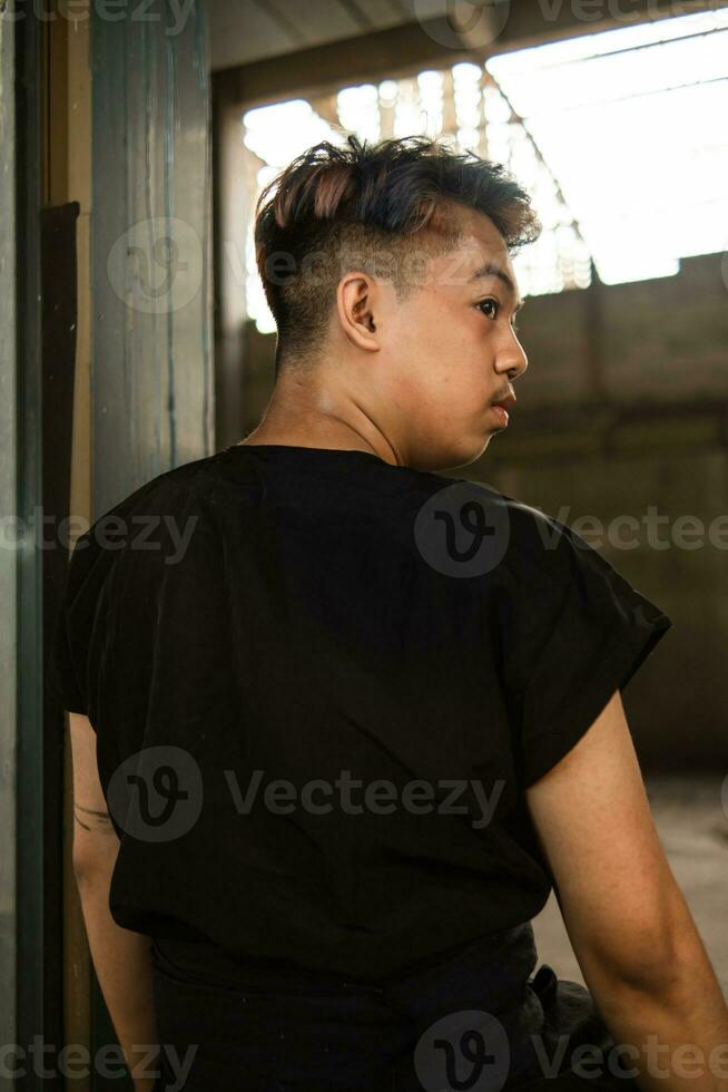 a ásia homem suspensão a partir de a ferro do a abandonado construção enquanto vestindo uma Preto camisa foto