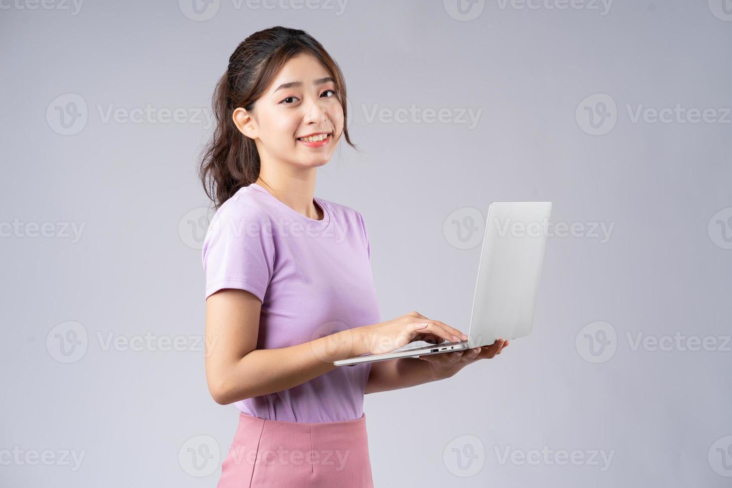 jovem mulher asiática usando laptop em fundo cinza foto