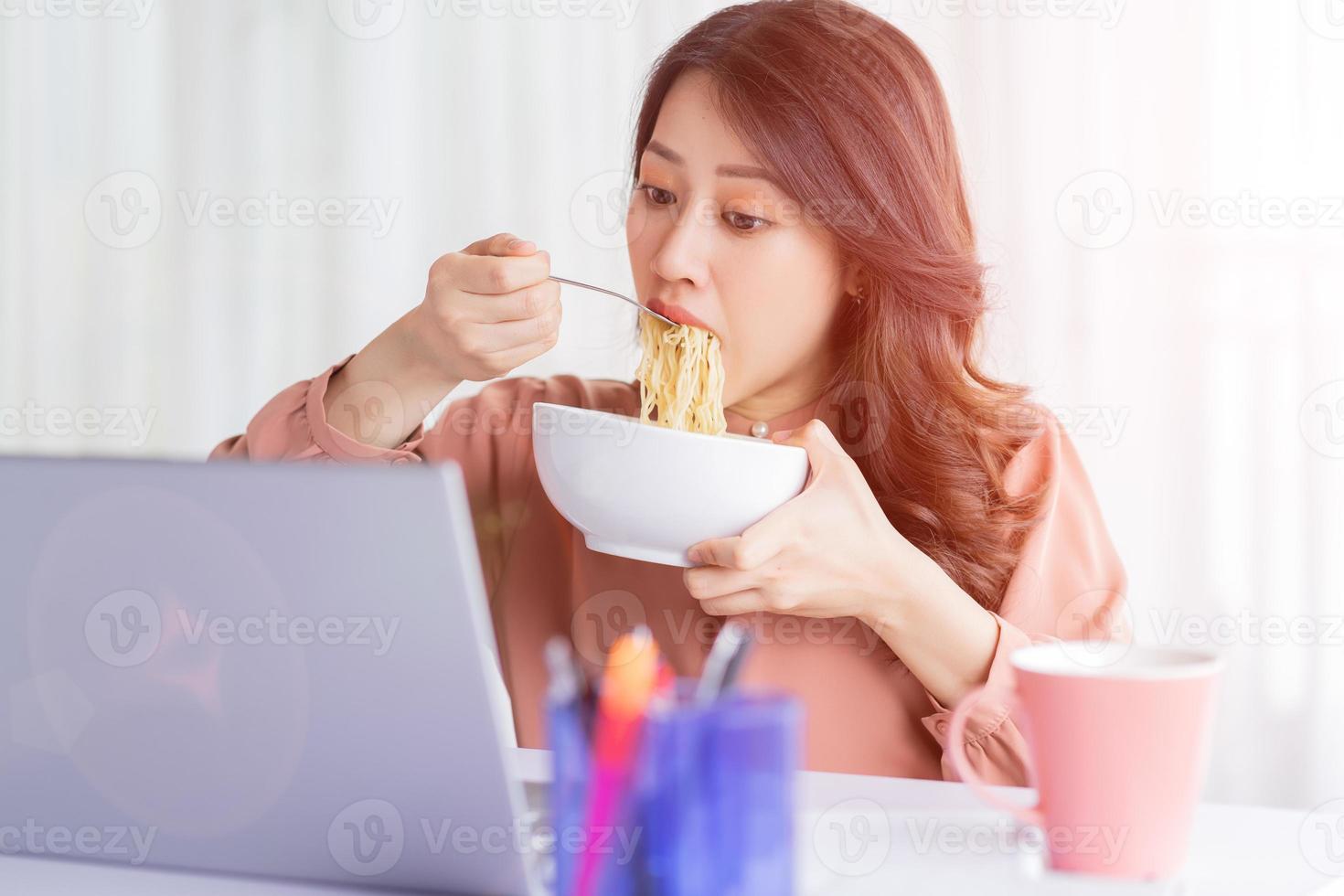 empresária asiática tem que comer macarrão enquanto trabalha foto