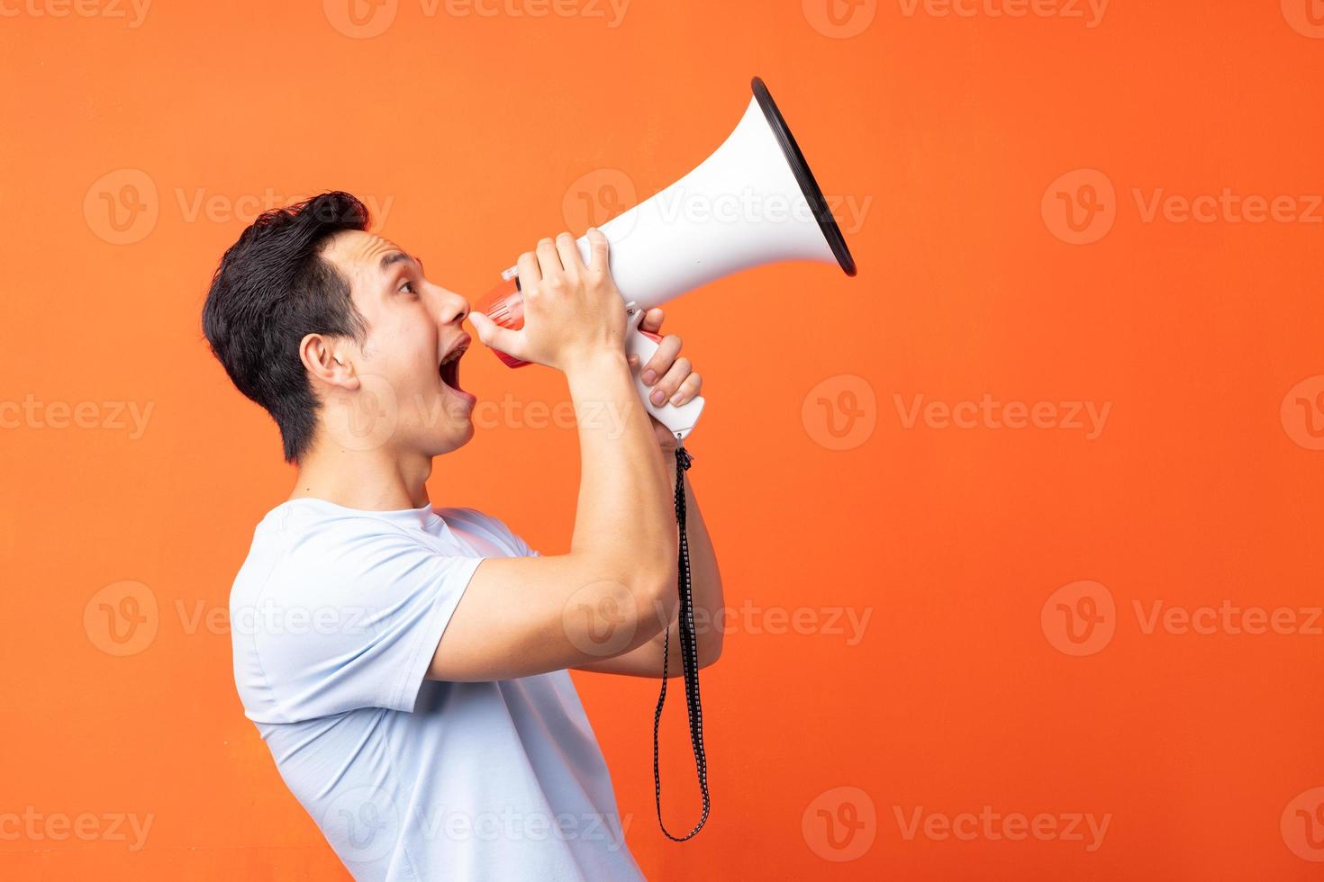 homem asiático segurando um megafone e gritando foto