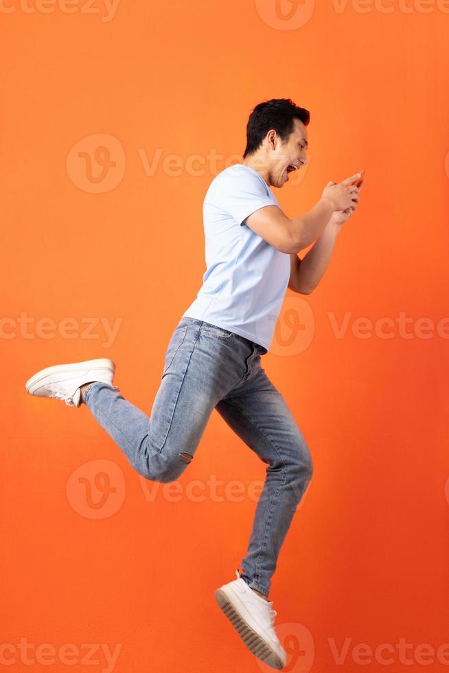 empresário asiático pulando e segurando o smartphone foto
