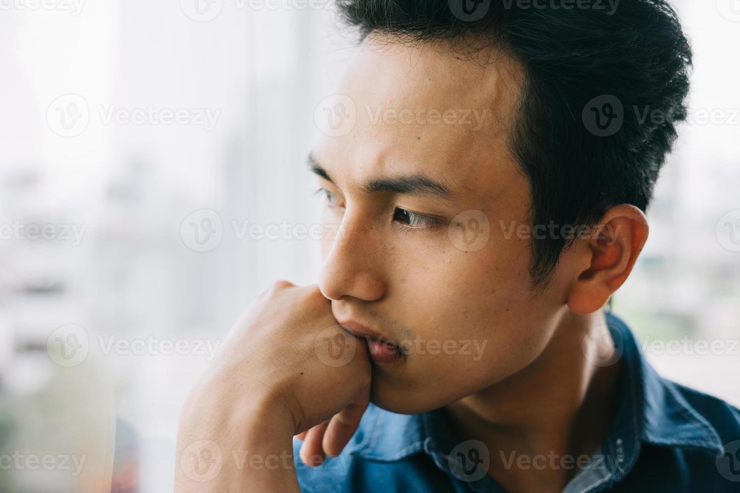 homem asiático triste na janela foto