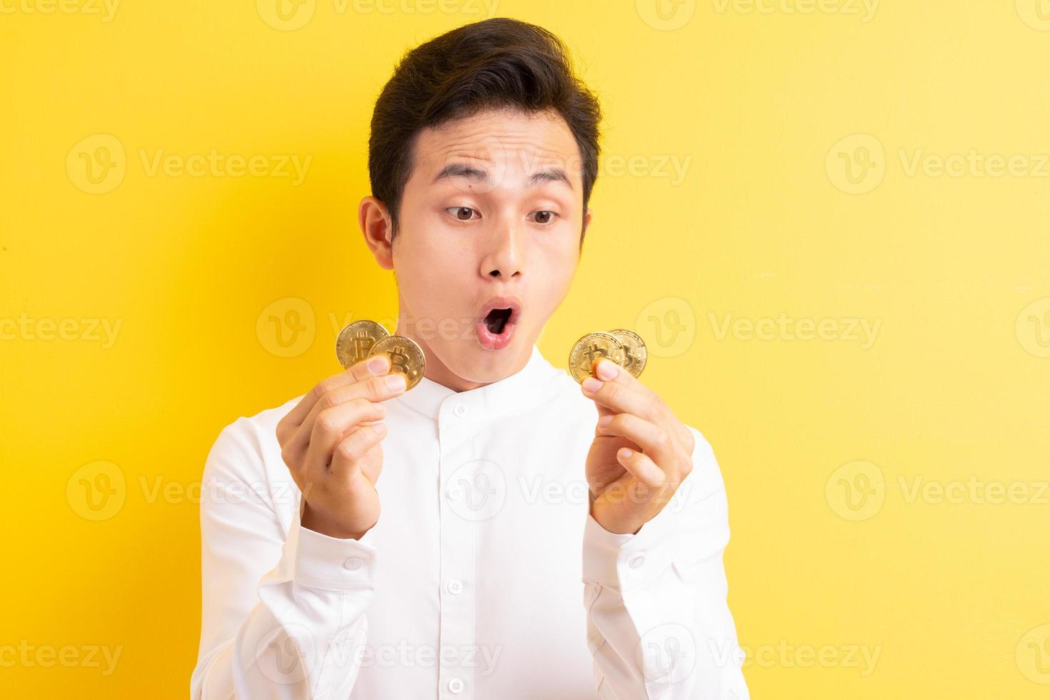 empresário asiático segurando bitcoin na mão com uma cara feliz foto
