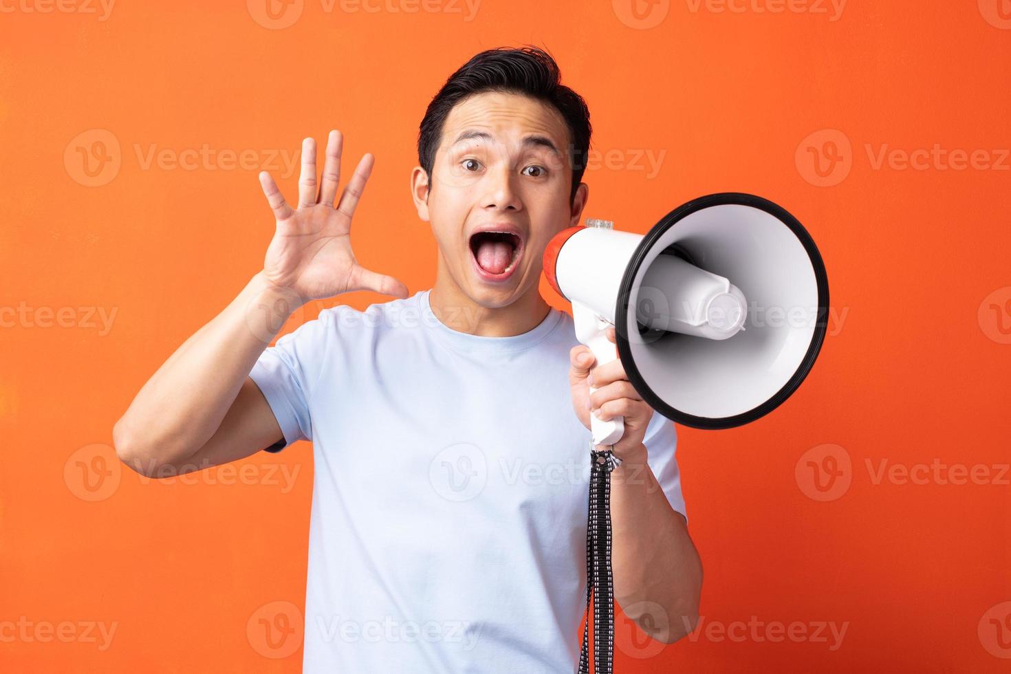 homem asiático segurando um megafone e gritando foto