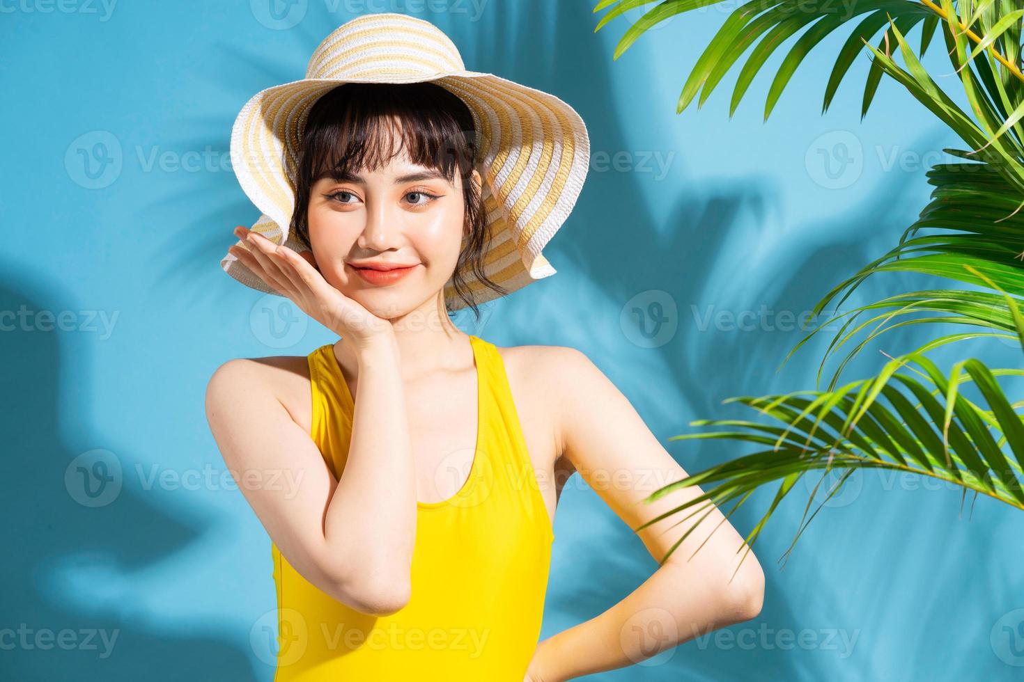 linda mulher asiática vestindo macacão amarelo sobre fundo azul e, conceito de verão foto
