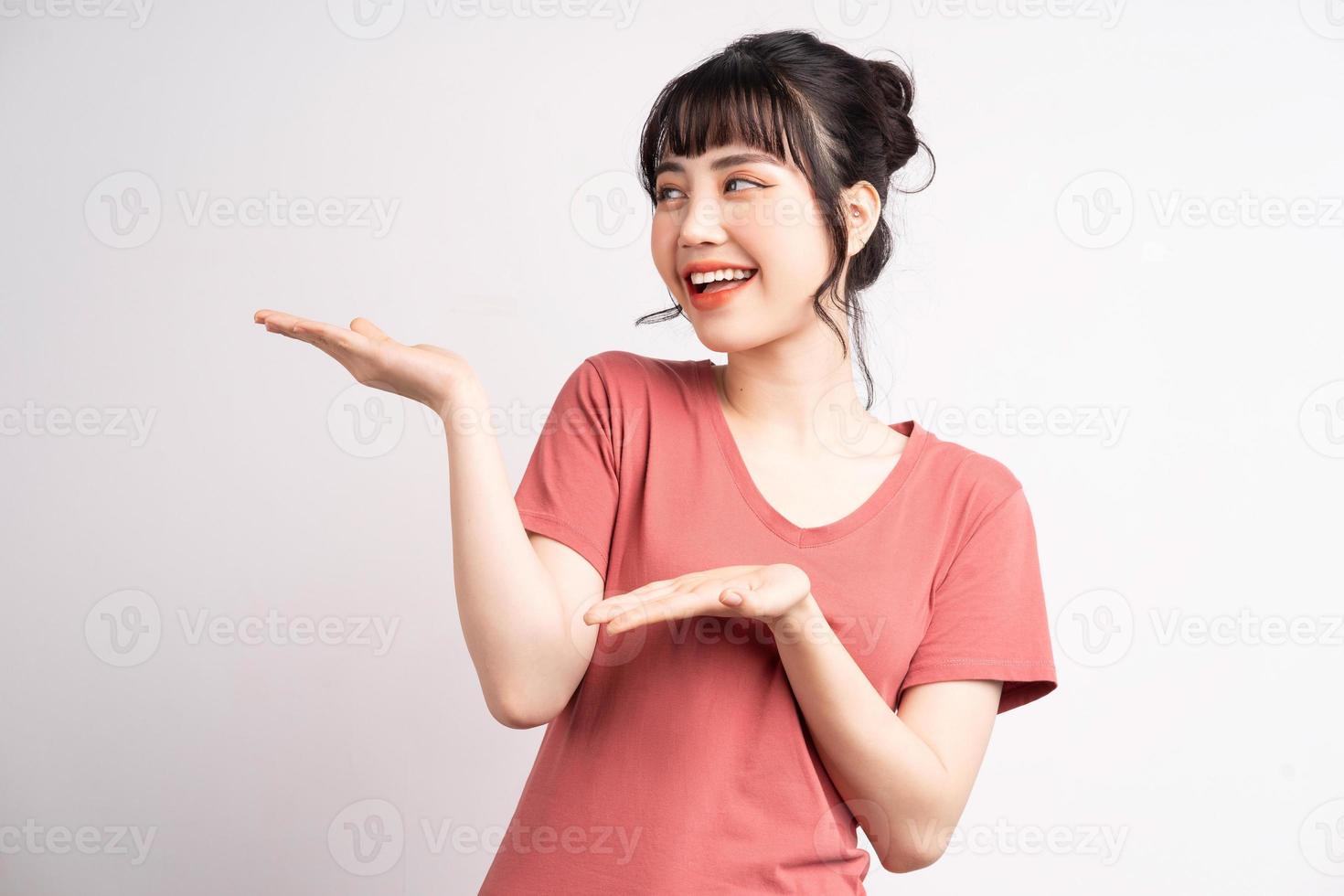 jovem mulher asiática posando em fundo branco, usando o dedo para apontar e mostrar, gesto com a mão foto