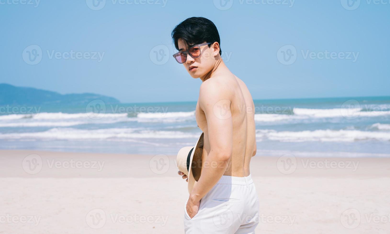jovem asiático caminhando na praia foto