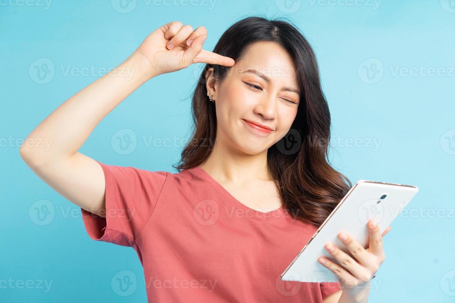 linda mulher asiática segurando o tablet na mão e pensando positivamente foto