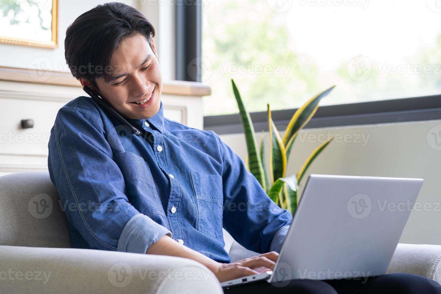 jovem asiático está ligando enquanto usa o computador foto