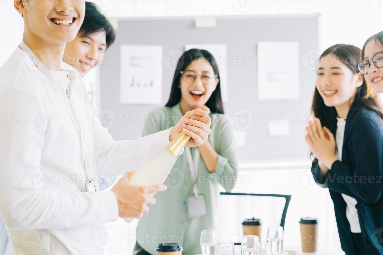 empresário asiático está abrindo champanhe para celebrar o ano novo com os membros do grupo empresarial foto