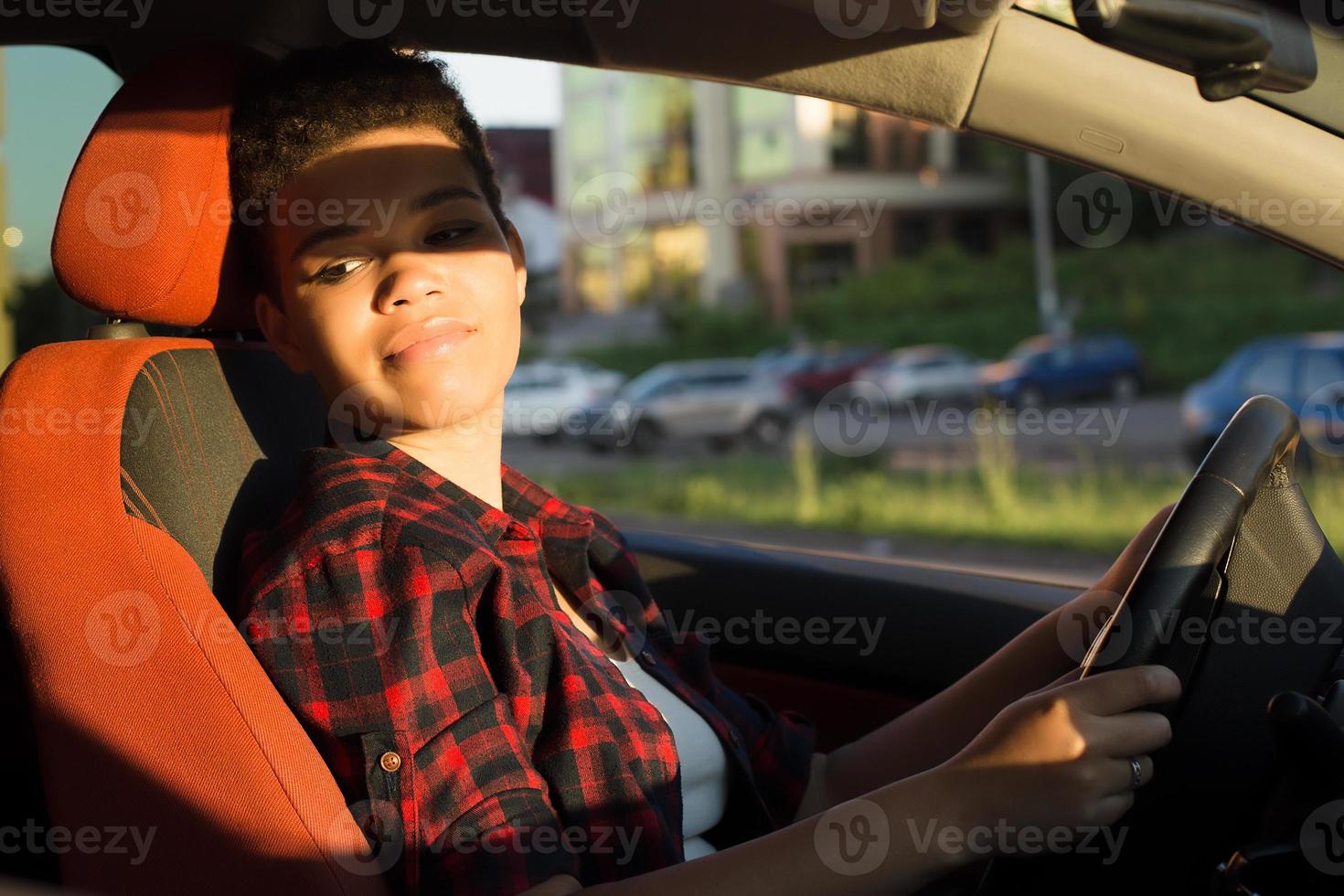 Mulher afro-americana séria e bonita com cabelo curto em um carro, estilo de vida foto