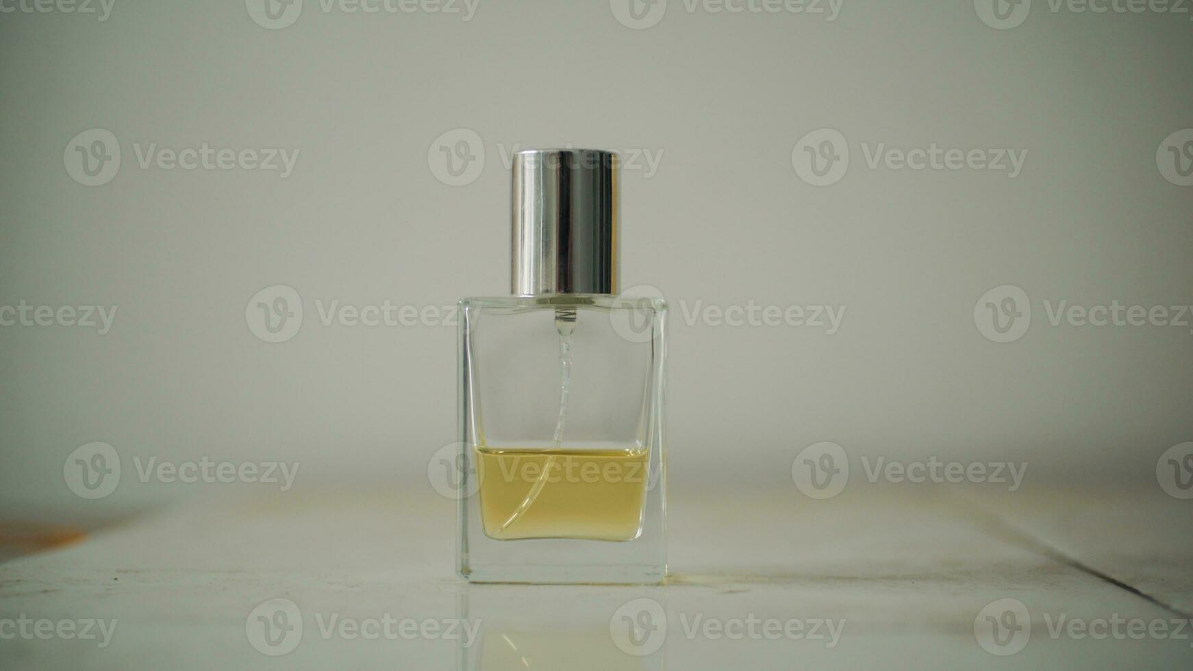 pequeno transparente perfume garrafa preenchidas com amarelo líquido em mesa com minimalista embaçado fundo. foto