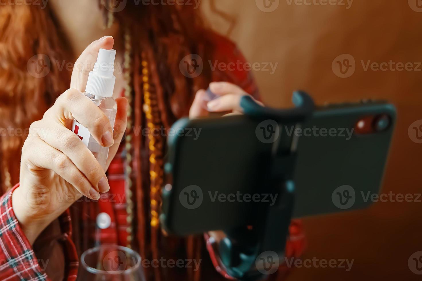 mulher borrifa anti-séptico em seu smartphone. foto