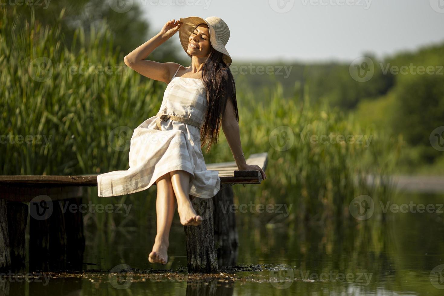 jovem relaxante no cais de madeira no lago foto