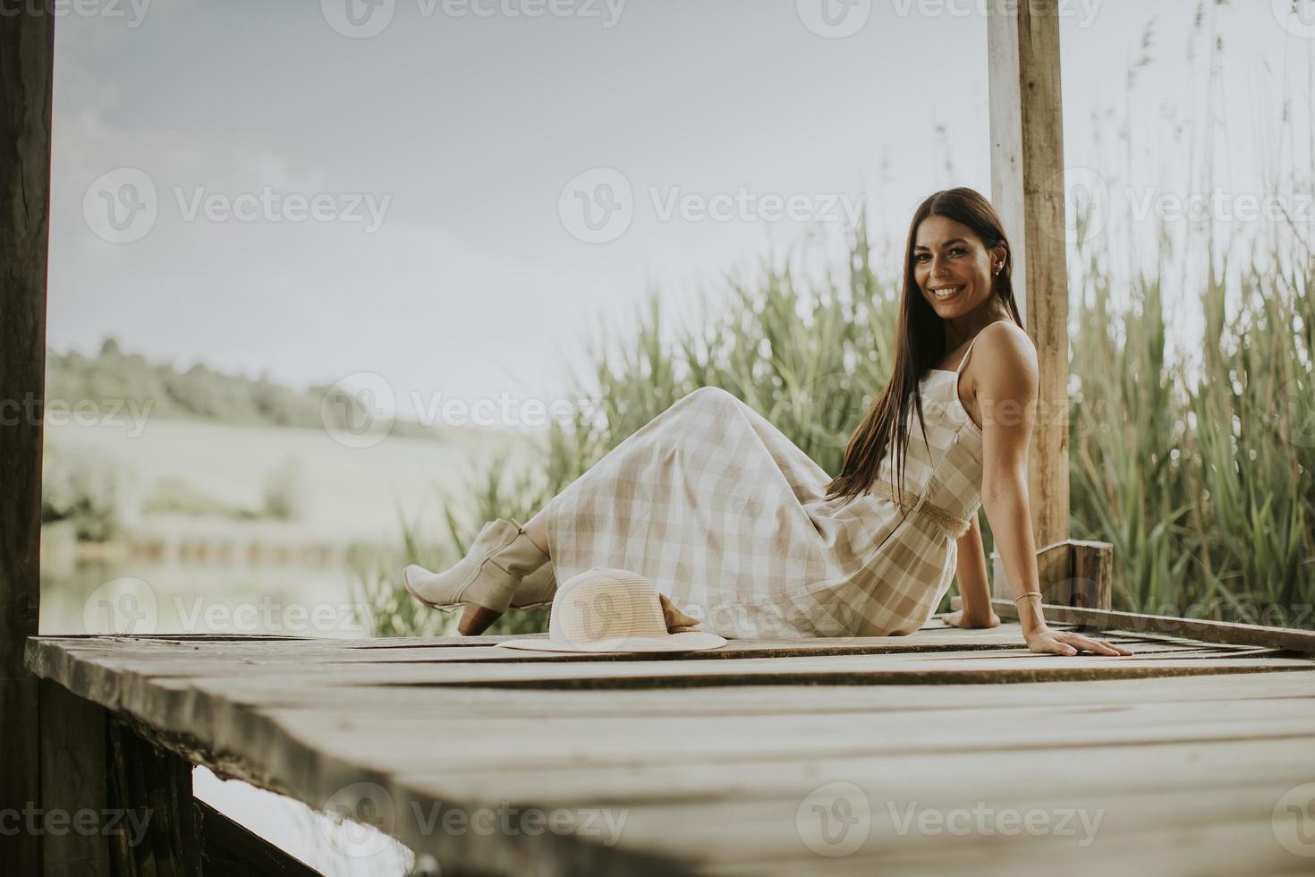 jovem relaxante no cais de madeira no lago foto