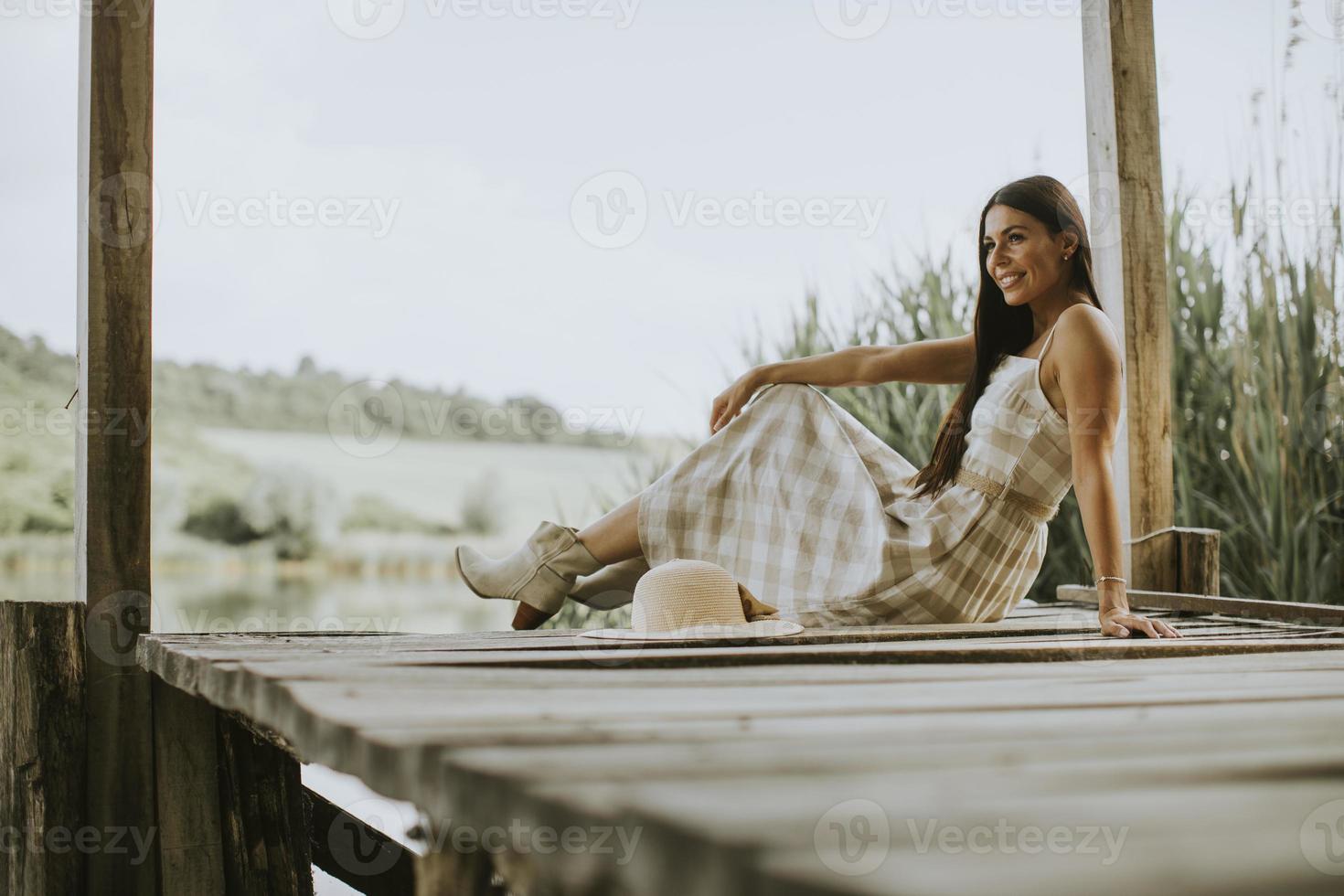 jovem relaxante no cais de madeira no lago foto