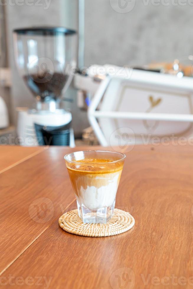 copo de café sujo ou leite frio coberto com uma dose de café expresso quente em uma cafeteria foto